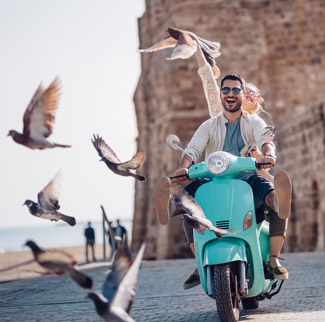 Man and woman on a scooter with birds flying around them