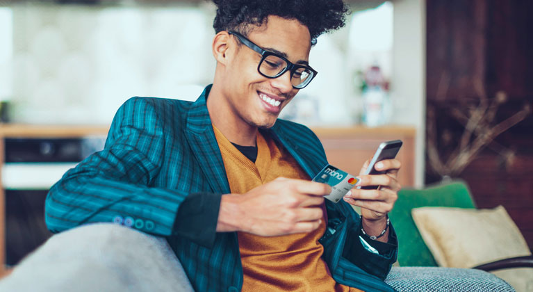 A man holds a mobile phone in one hand and MBNA credit card in the other.