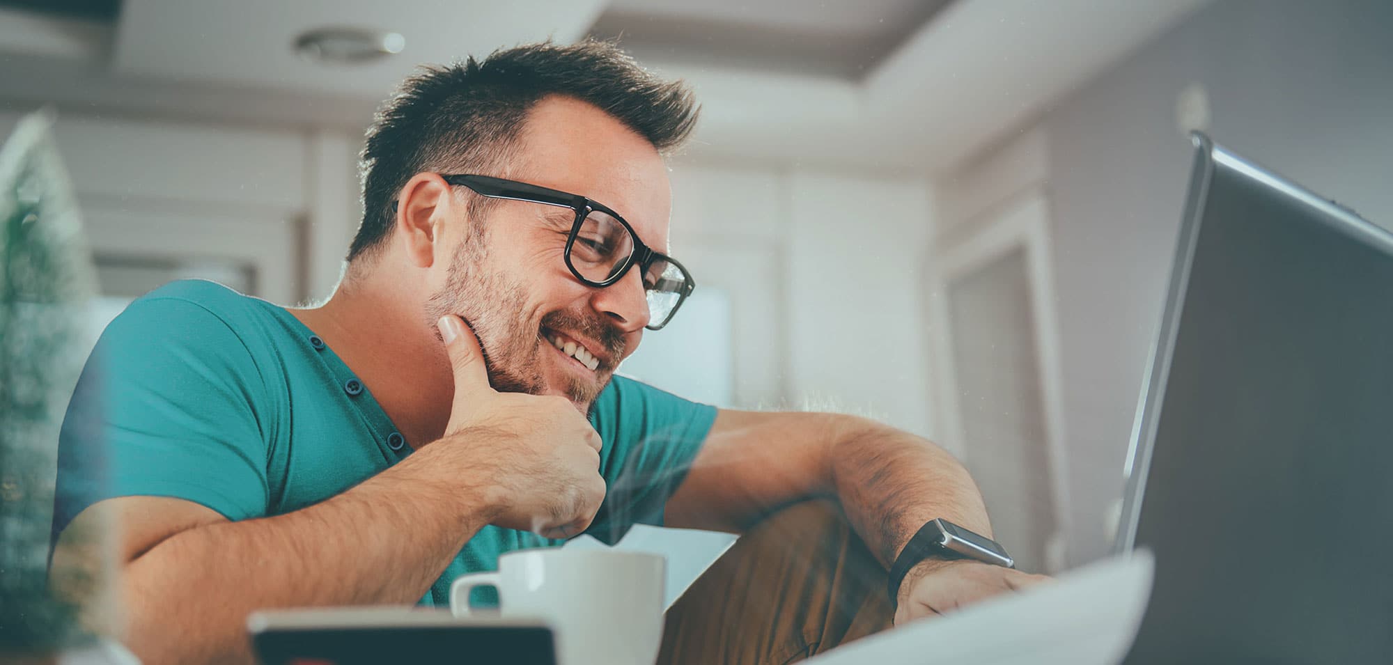 Man wearing glasses works on a laptop.