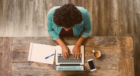 Man sat at a desk typing on his laptop