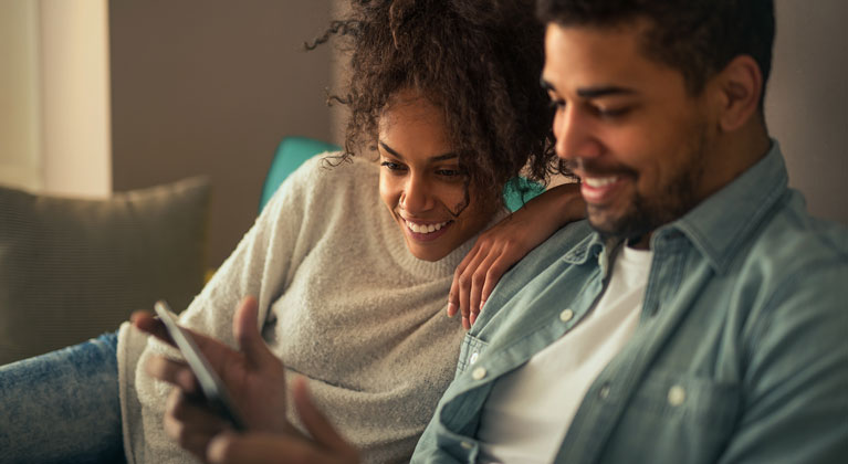 Couple on sofa looking at tablet.
