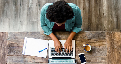 Man sat at a desk typing on his laptop