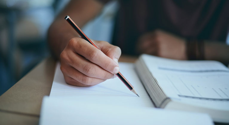 Person writing on paper with pencil