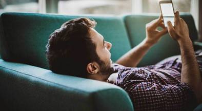 Man lying on sofa looking at his mobile phone