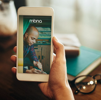 Hand holding smartphone with MBNA app on screen
