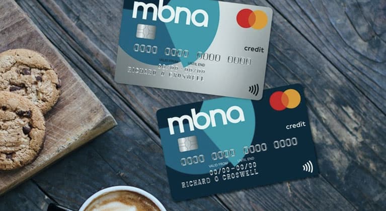 Two MBNA credit cards next to coffee and cookies.