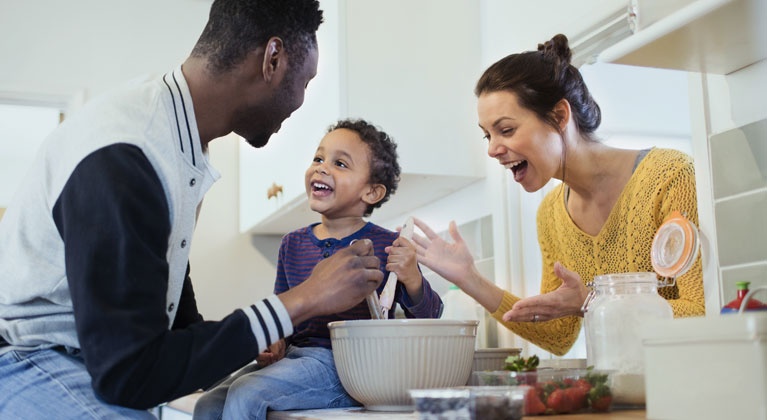 A happy man and a woman cooking with a child