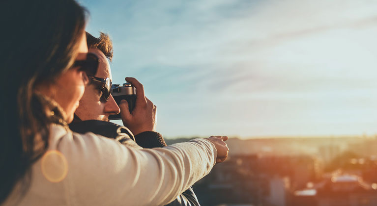 Couple take photographs over city.