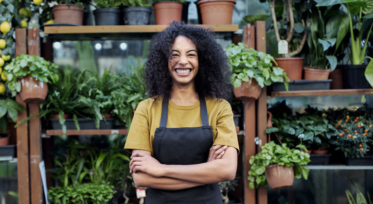 Happy woman standing in garden centre wearing an apron.