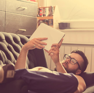 Man lying on sofa looking at a tablet
