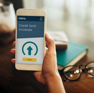 Hand holding smartphone with MBNA credit limit increase on screen