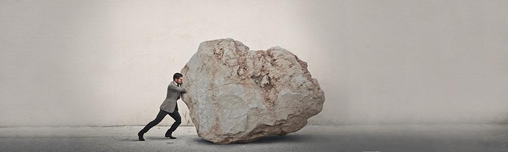Man pushing large boulder